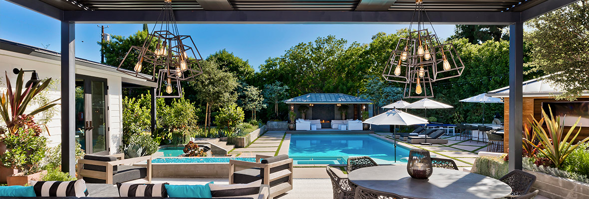 covered-patio-with-fireplace-and-a-swimming-pool-surrounded-by-trees-in-omaha-ne